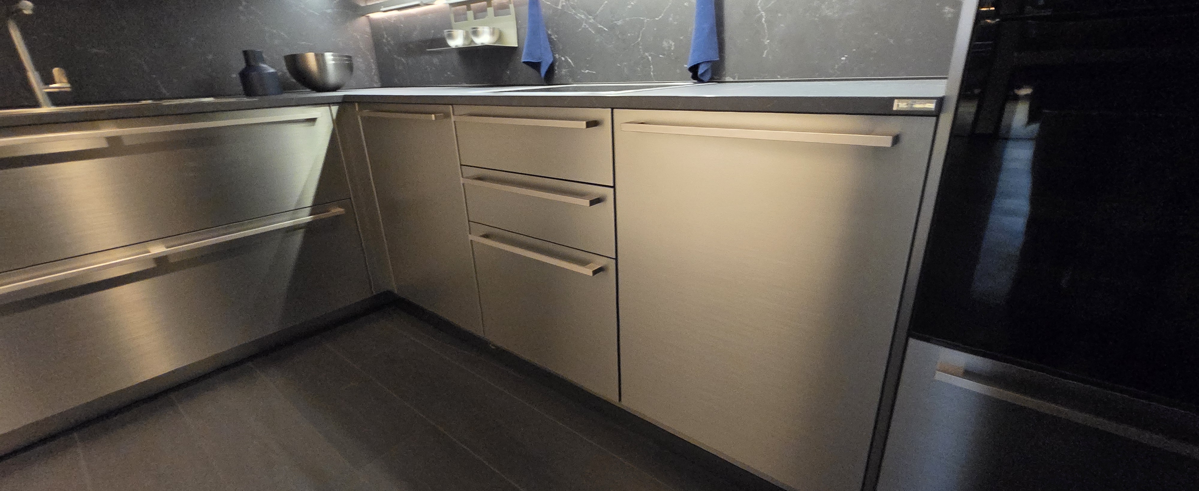 Close view of slim linear handles on brushed-metal cabinet fronts